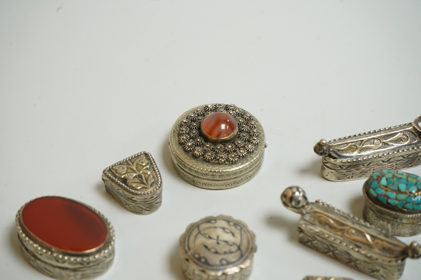 A collection of assorted pill boxes including one modern circular silver, a Mexican 925, six continental white metal, one inset with chalcedony and two with niello decoration and three other unmarked white metal pill box